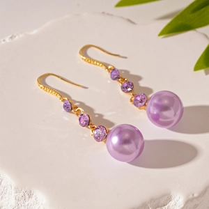 Detail of vintage gold earrings with purple crystals and a lustrous round purple pearl