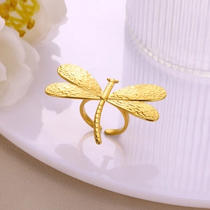 Detailed view of a golden dragonfly ring with engraved wing textures on white porcelain