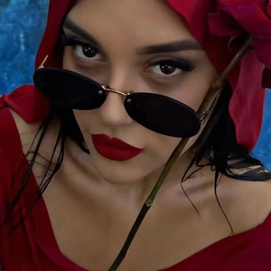Macro view of rimless oval sunglasses with gold metal bridge on model wearing red headscarf