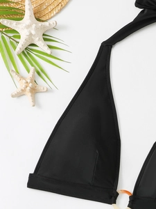 Detail of black halter bikini top with tortoiseshell resin ring and beach accessories