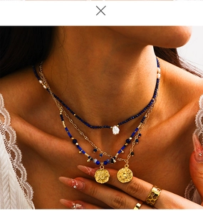 Close-up of layered necklace set with blue beads, baroque pearls and sun pendants