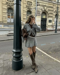 Détail d'un ensemble tricoté gris avec pull et jupe et bottes en daim marron