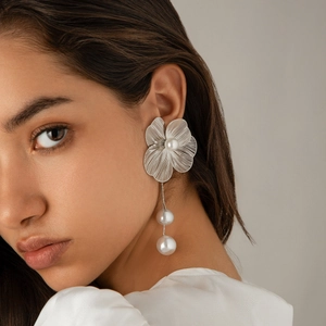 Close-up of model wearing silver flower petal earrings with hanging pearls and tassels