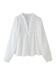 Détail d'un chemisier blanc en coton à col en V avec broderie et poignets volantés