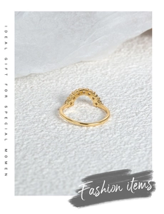 Detailed view of curved gold ring with inlaid cubic zirconia on white background