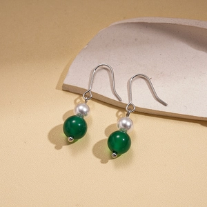 Close-up of elegant silver hook earrings with white pearls and round green beads