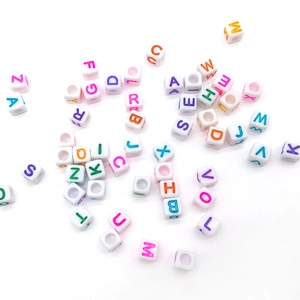 Macro view of white square acrylic beads with colorful uppercase letters for DIY jewelry