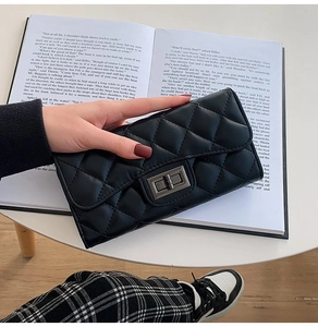 Detailed view of a black quilted leather long wallet with a classic metal turn-lock closure