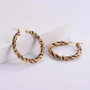 Elegant gold twisted hoop earrings with a textured rope design on a white stone base