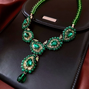Vue macro d'un collier vintage en Y avec cristaux verts et monture dorée