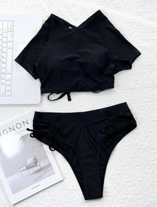 Flat lay of black high waist bikini set featuring drawstring details and short sleeve crop top