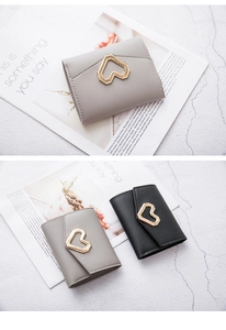Detail view of heart-shaped gold buckle on gray and black faux leather wallets