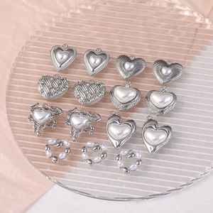 Détail de breloques en forme de cœur argenté et pendentifs perles pour création bijoux