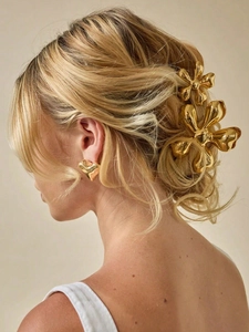 Detail showing high-shine gold metal flower hair claw clip with heart stud earring set