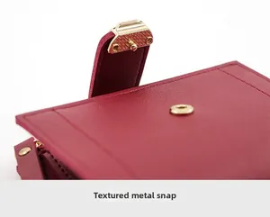 Detail of burgundy textured leather wallet featuring a premium golden metal snap button