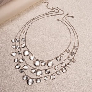 Detailed macro view of triple-layered silver necklaces with hammered circular pendants