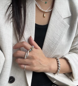 Detailed view of layered 925 silver minimalist rings and bracelets on a model's hand