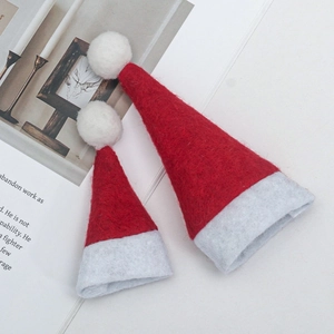 Mini felt Christmas hats in two sizes on book page for wine bottle and cutlery decor