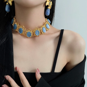 Model wearing vintage gold floral jewelry set with oval blue stones and earrings