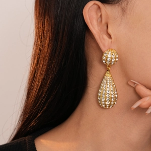Elegant gold-tone teardrop earrings with crystal rhinestones on female model