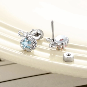 Silver bow and shell earring with blue zircon star on a ceramic display tray