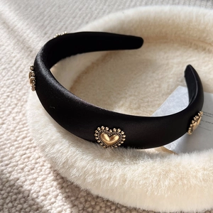 Elegant black satin headband featuring gold heart-shaped metal accents on a plush base