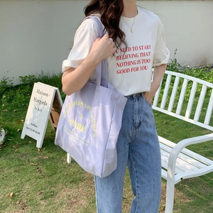 Detail of light purple canvas tote bag with yellow Paris embroidery on casual outfit