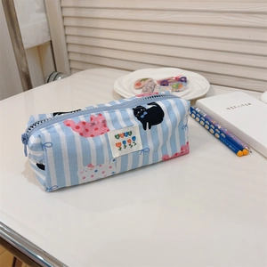 Détail d'une trousse à rayures bleues avec des chats et un écusson BEST en forme de cœur