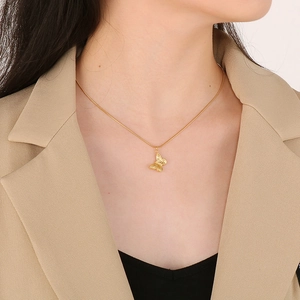 Close-up of a gold-tone butterfly pendant necklace worn by a model on the collarbone