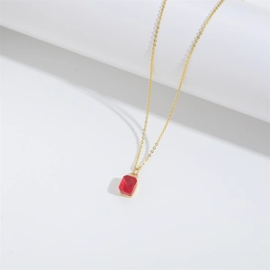 Detailed macro view of a rectangular red gemstone pendant on a fine gold chain necklace