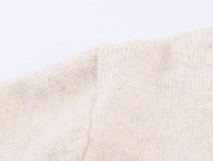 Close-up of beige knit cardigan showing high-quality shoulder stitching and wool texture