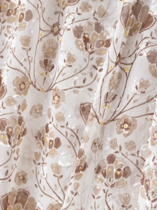 Détail macro du tissu mousseline blanc avec fleurs brunes et pois dorés brillants