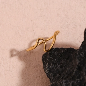 Detailed macro view of 18K gold plated stainless steel wave ring on a textured black rock