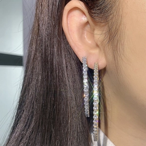 Close-up of oversized gold and silver hoop earrings with shimmering pave-set cubic zirconia