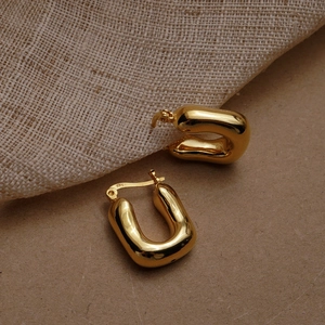 Detail of chunky gold U-shaped S925 sterling silver earrings with a polished finish