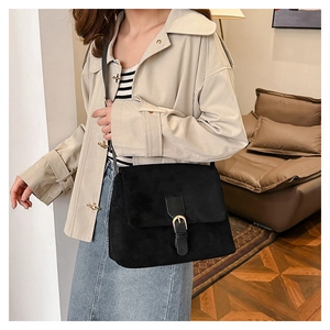 Detail of matte black suede shoulder bag with golden buckle on a stylish model