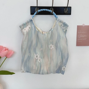 Detail of floral embroidery and braided rope handle on a soft tulle fabric handbag