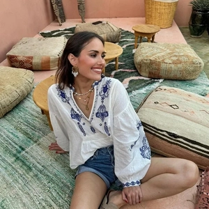 White boho V-neck long sleeve top with blue floral embroidery on light cotton fabric