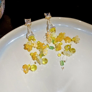 Close-up of handmade floral tassel earrings with yellow beads and sparkling crystals