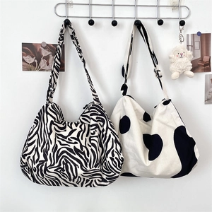 Close-up of corduroy cow print crossbody bag with plush charm and wide strap