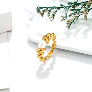 Twisted gold titanium ring with a natural freshwater pearl on a white pedestal