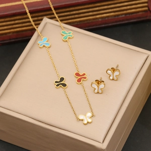 Parure papillon dorée avec pendentifs colorés présentée sur un écrin à bijoux