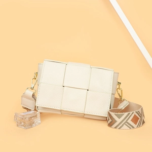 Close-up of white woven leather crossbody bag with geometric pattern wide strap