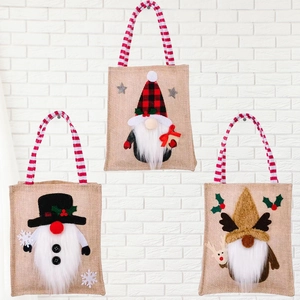 Three Christmas burlap gift bags featuring gnome, snowman, and reindeer plaid designs