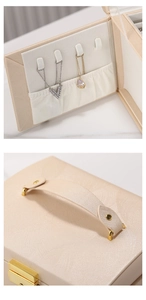 Detail view of beige PU leather jewelry box with gold clasp and necklace storage hooks