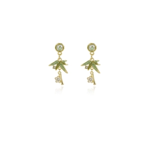Detailed close-up of golden bamboo leaf earrings with white floral charms and soft reflections