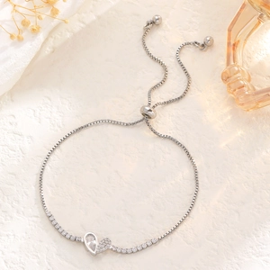 Detail of adjustable silver tennis bracelet with heart charms and sparkling crystals