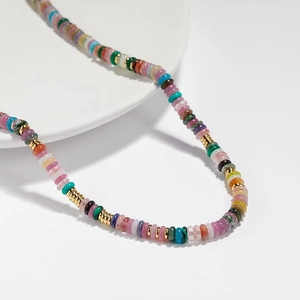 Close-up of bohemian beaded necklace with multi-color stones and golden metal spacers