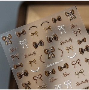 Detailed view of 5D nail art stickers featuring brown bows and pearl chain textures