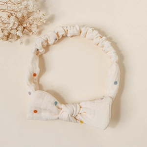 Detail of soft cream cotton baby headband featuring colorful polka dots and a bow knot